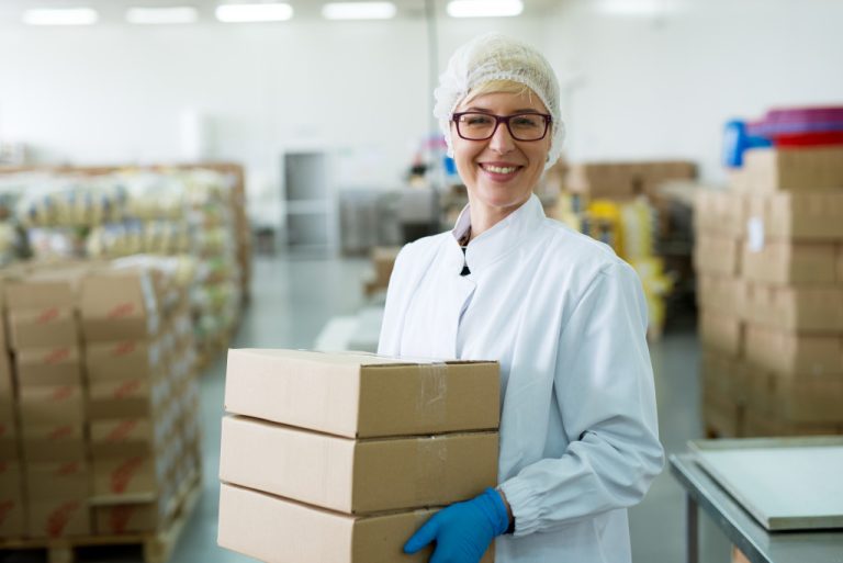 woman holding a box inside a warehouse while wearing PPE