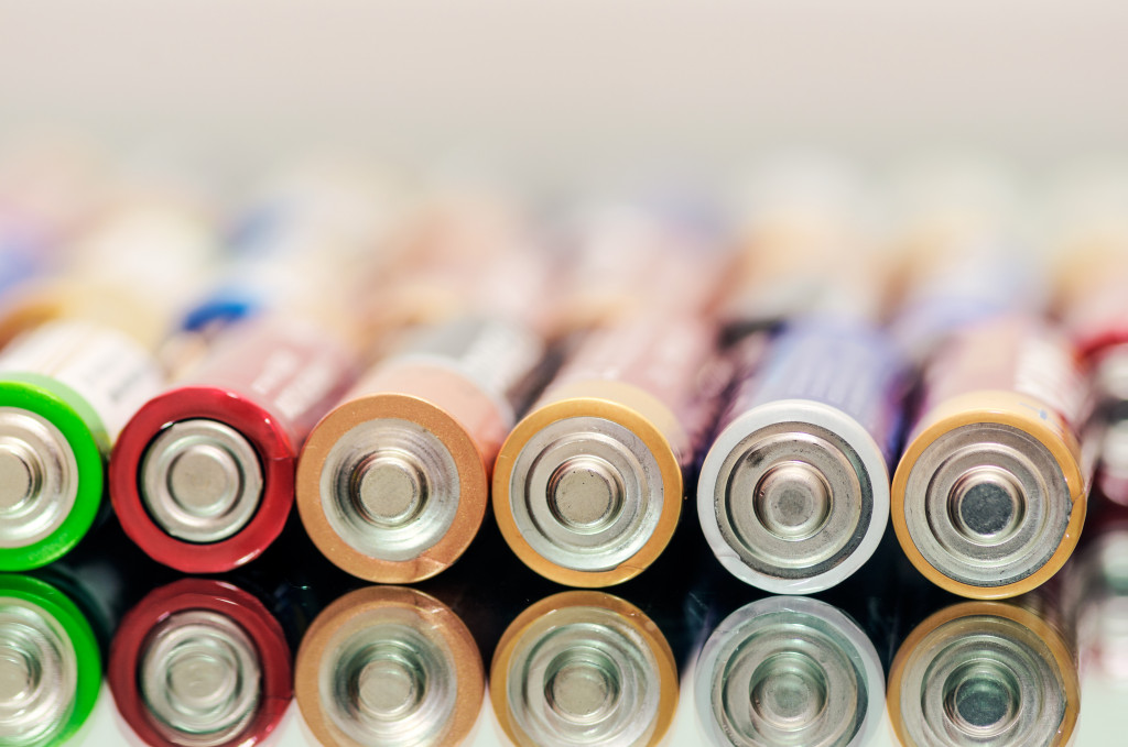 Closeup of pile of used alkaline batteries. Close up colorful rows of selection of AA batteries energy abstract background of colorful batteries. Alkaline battery aa size. Several batteries in rows.