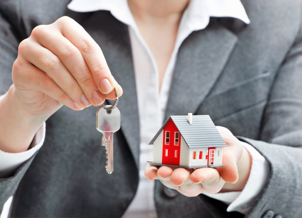 a person holding a key and house figurine