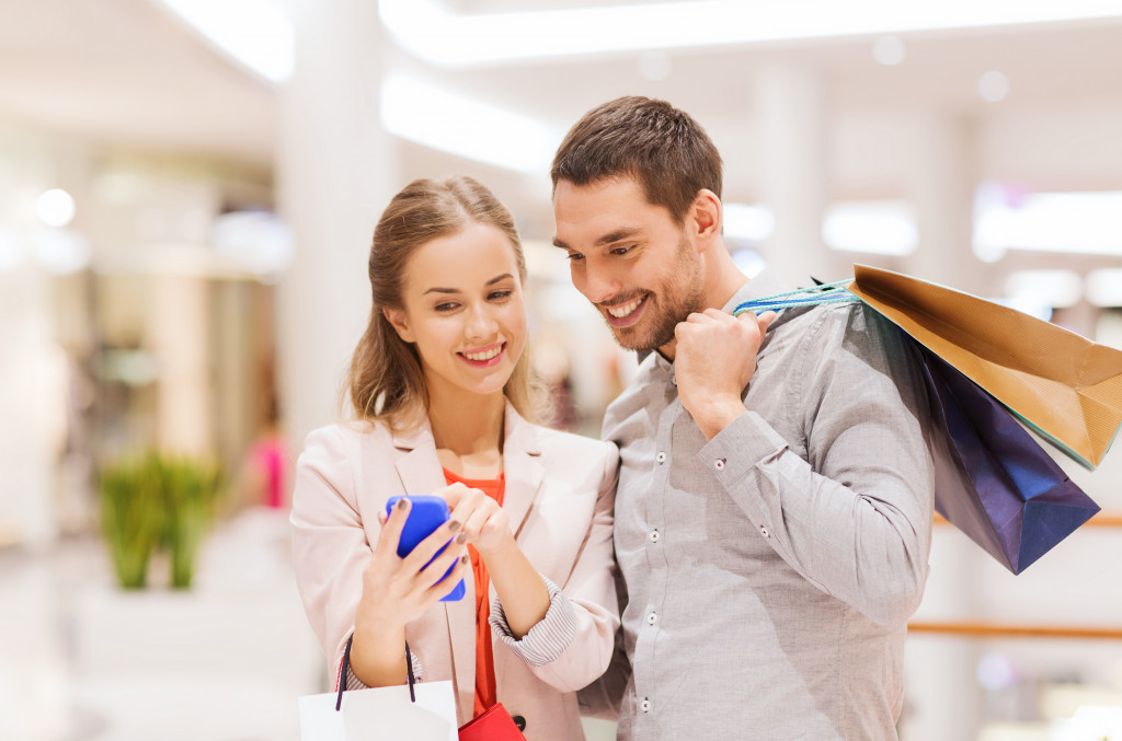 Smiling customers using a smartphone to check products in a business.